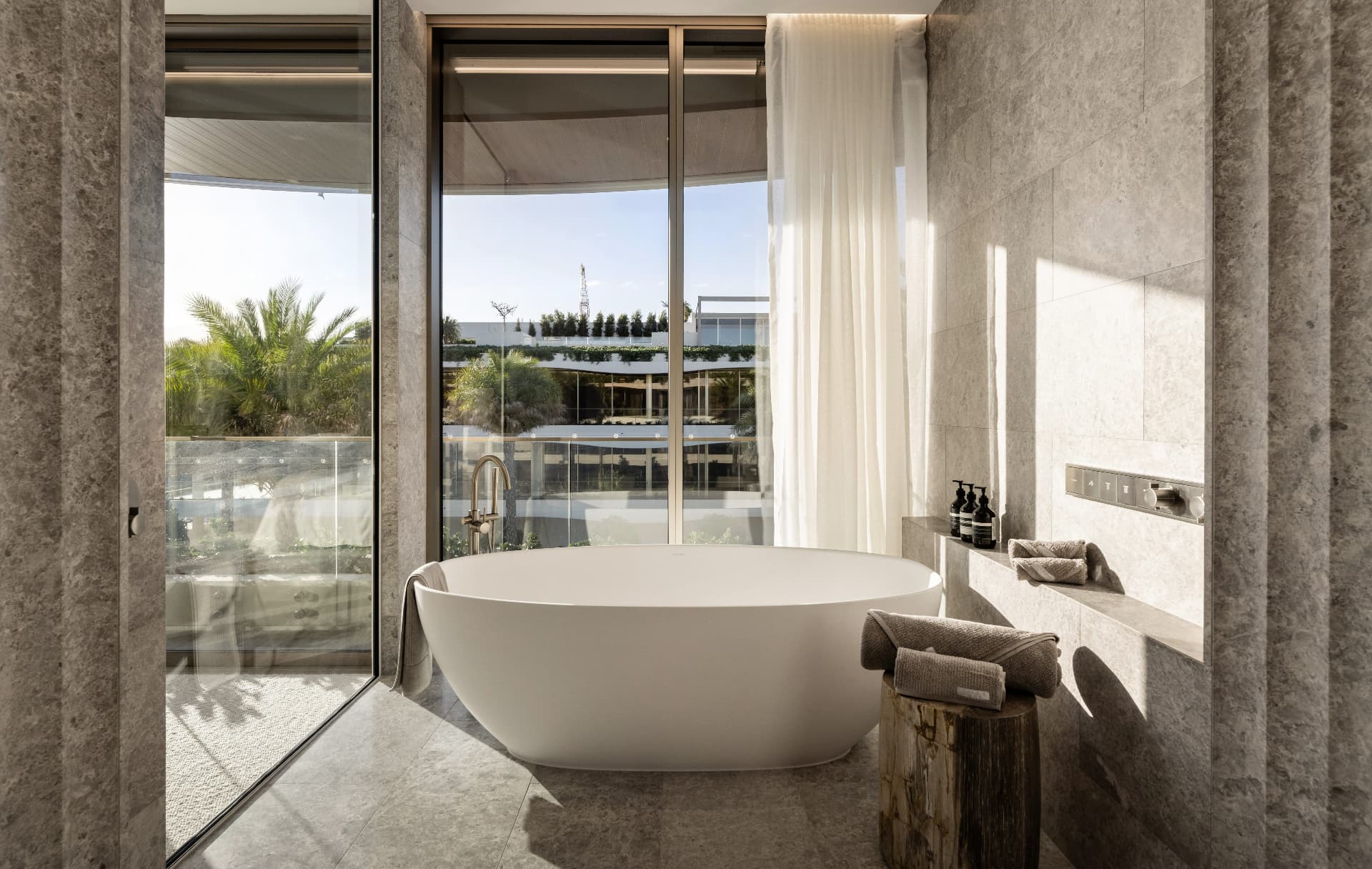 Freestanding bath with floor-to-ceiling glass overlooking the terrace